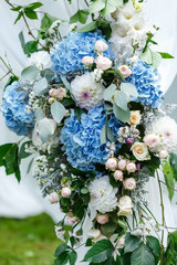 Wedding ceremony decorations: close-up decor of arch, decorated with crysanthemums, roses, hydrangeas and greenery. A lot of flowers in white and blue style