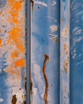 Detail of peeling paint and markings on colorfully painted industrial cargo container