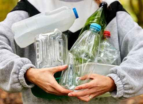 Woman holding armful of used plastic packaging and bottles