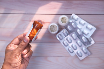 man hand holding pill contianer, top view 