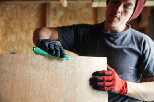 Carpenter sanding down wood for a smooth finish