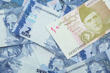 A close up image of a gray and pink ten Pakistani rupee bank note with Brazilian two reais bank notes in macro