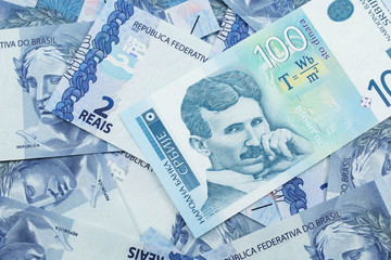 Fototapeta premium A close up of a blue and white, one hundred Serbian dinar bank note on a background of Brazilian two reais bank notes