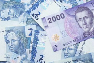Fototapeta premium A close up image of a purple two thousand peso bank note from Chile on a bed of Brazilian two reais bank notes in macro