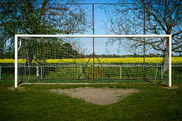 Rural soccer goal with yellow rape field and blue sky
