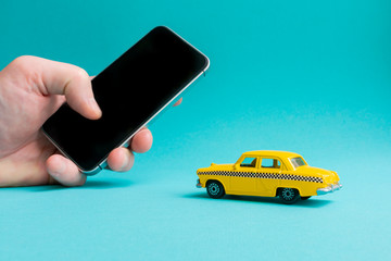 Taxi mobile online application concept.  Hand holding smart phone.Toy yellow taxi car model.