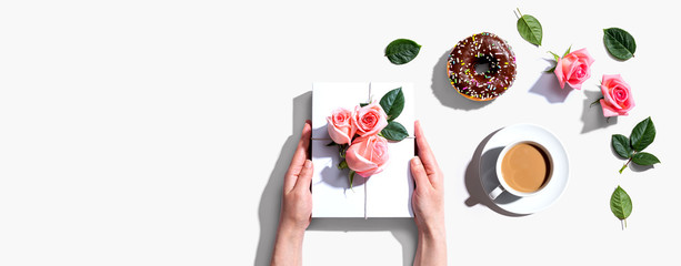Female hands holding a gift box with pink roses overhead view - flat lay