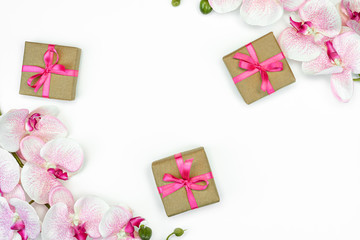 flatlay of Gift present boxes pink ribbon and orchid flowers on white background top view. spring concept. Copy space