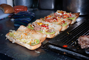 Fast food prepared on the street in Guatemala, Central America, bread with sausages, cabbage, avocado and sauces, called Shuco Chapina version of hot dog, danger of contagion of diseases and Covid 19.