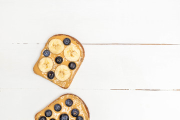 Homemade peanut butter, blueberry and banana sandwich on white wooden table
