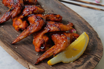 
fried chicken wings with spices and sesame seeds on a wooden plate.
