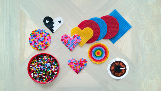 Step-by-step instructions for thermo mosaic: step 1.Set of several circle,square and heart-shaped forms with pins,jar and container lid with beads.Concept of quiet family game with children at home - Powered by Adobe