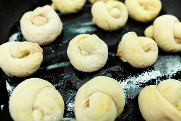 Home made sweet yeast buns laid out on an oily baking tray.