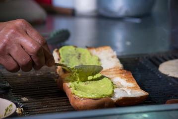 Hands of man preparing roasted bread wings fathoms on the street called Shuco in Guatemala, version of the Hot Dog