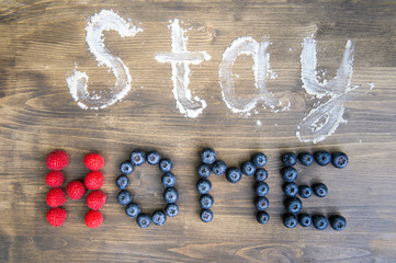 The concept of the word image - stay home written on a wooden background with fruits and flour.