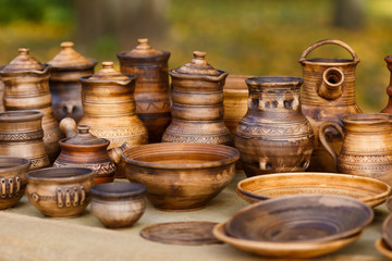 A lot of pottery - pots, jars, bowls, plates with ornaments are standing on the stall. Handmade dishes made of clay