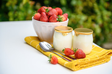 Two glasses of natural yogurt on a white background decorated with mint and strawberries.