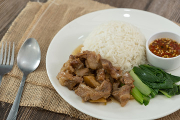 Stewed pork with rice, spicy sauce and vegetables. Wooden table