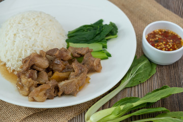 Stewed pork with rice, spicy sauce and vegetables. Wooden table