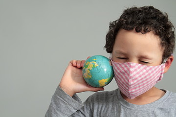 child with face dust mask and globe coronavirus COVID-19 on grey background stock photo