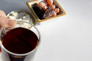 The girl holds a mug of tea, and on the surface of the table are three pieces of sugar in the form of different shapes, a heart.