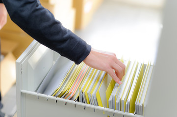 机の引き出しの中から、書類を探している手のアップ	