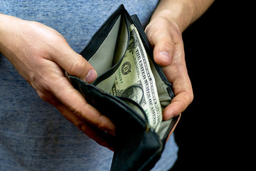 The man holds an empty and worn wallet with one dollar in it. Consequences of a crisis or pandemic.