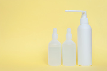 Three white plastic bottle with an antiseptic on a yellow background. The concept of personal hygiene and protection.