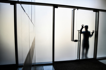 persona in silhouette attraverso la vetrata mostra se stesso e il palmo delle sue mani