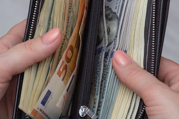 Female hands hold a wallet full of money. Unexpectedly found cash. Wealth and prosperity concept