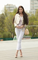 Fashion style portrait of young beautiful elegant brunette woman walking at city streets on a windy...