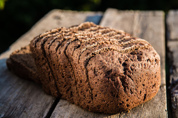 Fresh rye bread or whole grain bread on dark table background. Healthy baked bread in slices, whole...