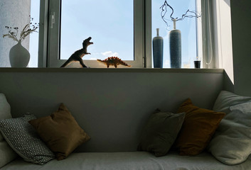 Toy dinosaurs on windowsill in modern apartment