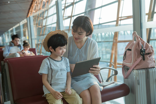 A young mother and son in the airport lounge see tablets