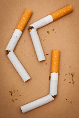 three broken cigarette on a brown background