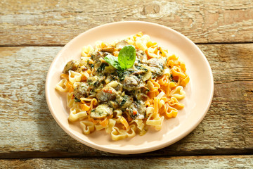 Pasta with mushrooms in a creamy sauce with spinach on a wooden table.