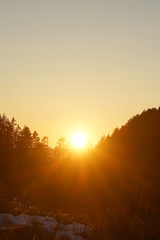 Fototapeta na wymiar Sun goes down behind forest mountain.