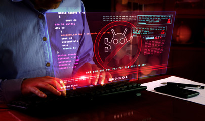 Man typing on keyboard with virus detected alert on hologram screen