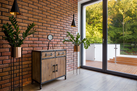 Wooden dresser in room with brick wall