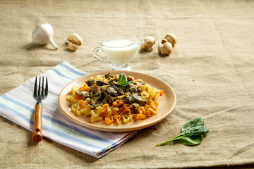 pasta with mushrooms in a creamy sauce with spinach on a linen tablecloth on a napkin and a fork nearby. copy space.