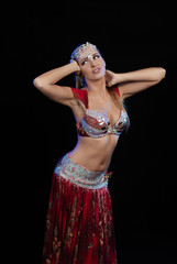 Young woman belly dancer in a red oriental costume on a black background