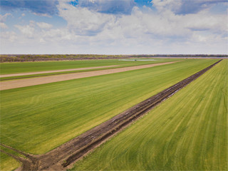 Fototapeta na wymiar Aerial drone image of tractor spraying soil and young crop in springtime in field