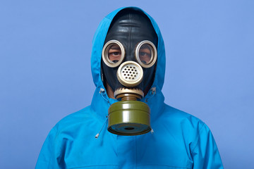 Image of ecologist wearing gas mask frights with pouring dangerous chemicals to ground, world...