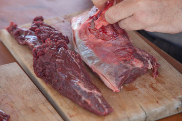 fresh deer cutted with knife on a wooden dish.