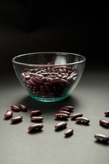 Glass jar with red beans on a black background.