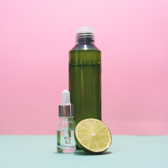 Cosmetic bottles and lime on the pink and mint or green background.