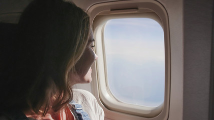Happy girl at the window of an airplane.