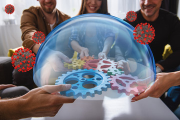 Business team connect pieces of gears protected by a glass sphere from coronavirus covid-19....