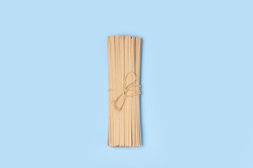 Top view raw whole grain spaghetti pasta tied with rope on blue background
