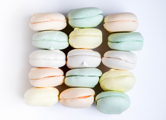 Air marshmallows in pastel shades on a white background. Gentle pastel colored zephyr in light key